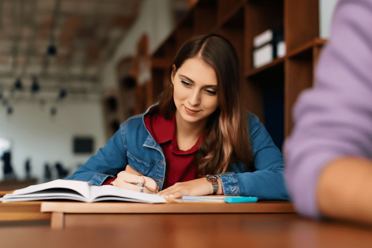 Une jeune femme écrit un roman dans une bibliothèque